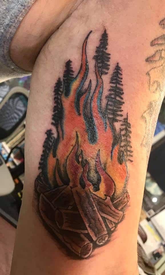 campfire and pines tattoo arm