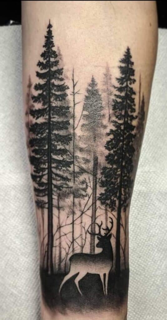 black and white deer in pine forest on forearm tattoo