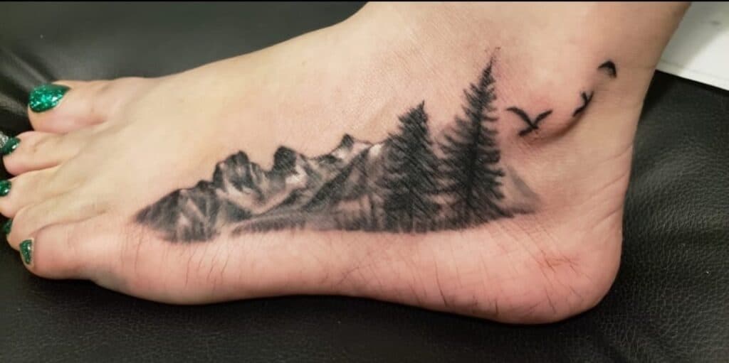 mountains nature tattoo on side of foot black and white