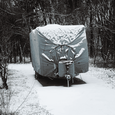 camper trailer in snow with rv cover on top