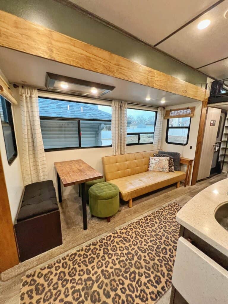 camper interior with leopard print rug, leather couch, sage green wall